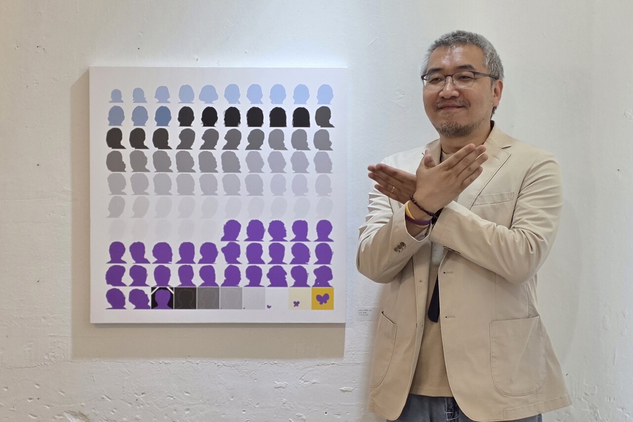▲ 이정헌 작가(인권운동가 김복동 탄생 100주년 기념전시 ‘김복동 100’ 총괄기획자)가 자신의 작품 옆에서 손으로 큰나비를 만들어 보이고 있다.